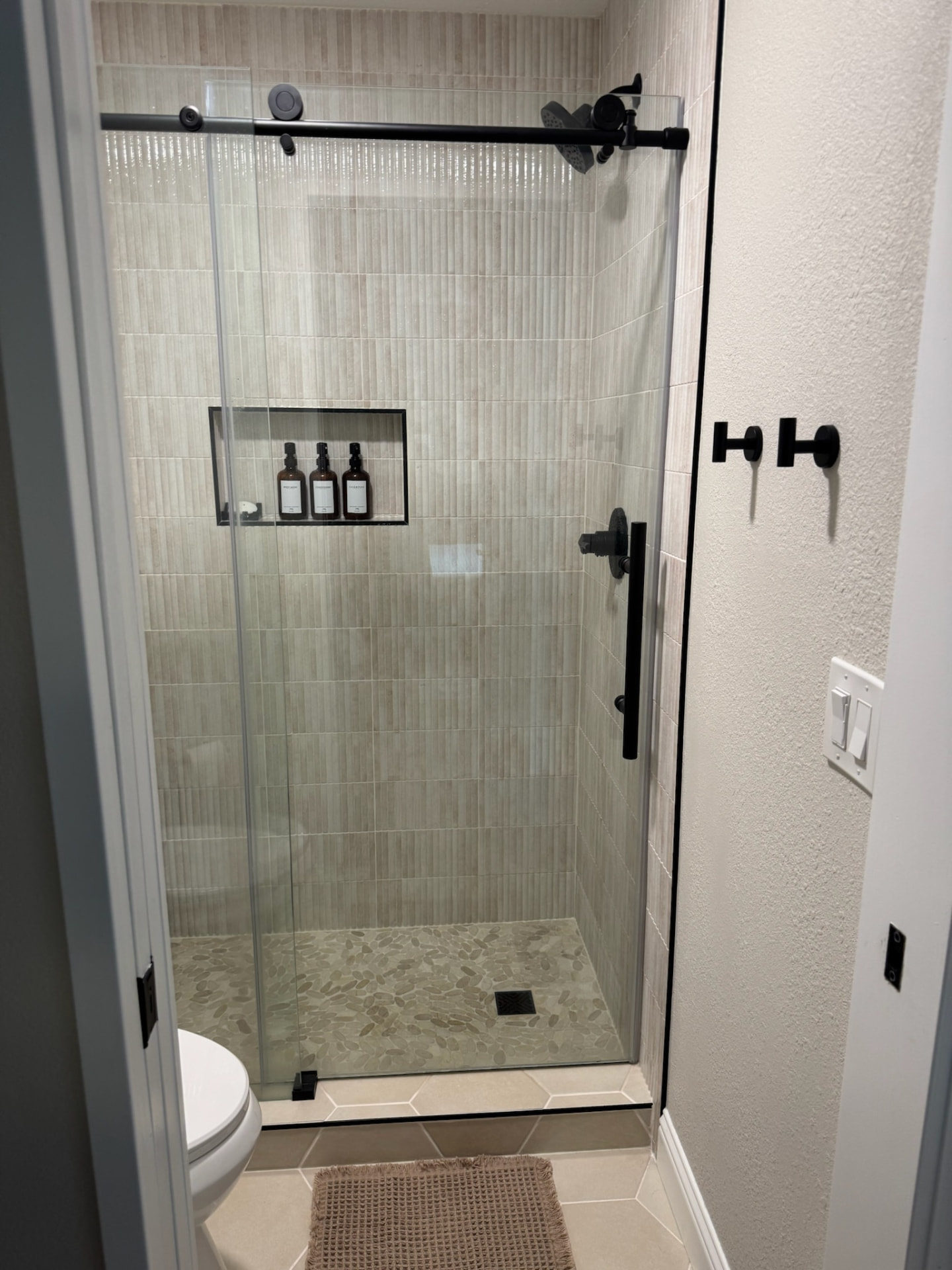 Glass sliding shower door with black hardware