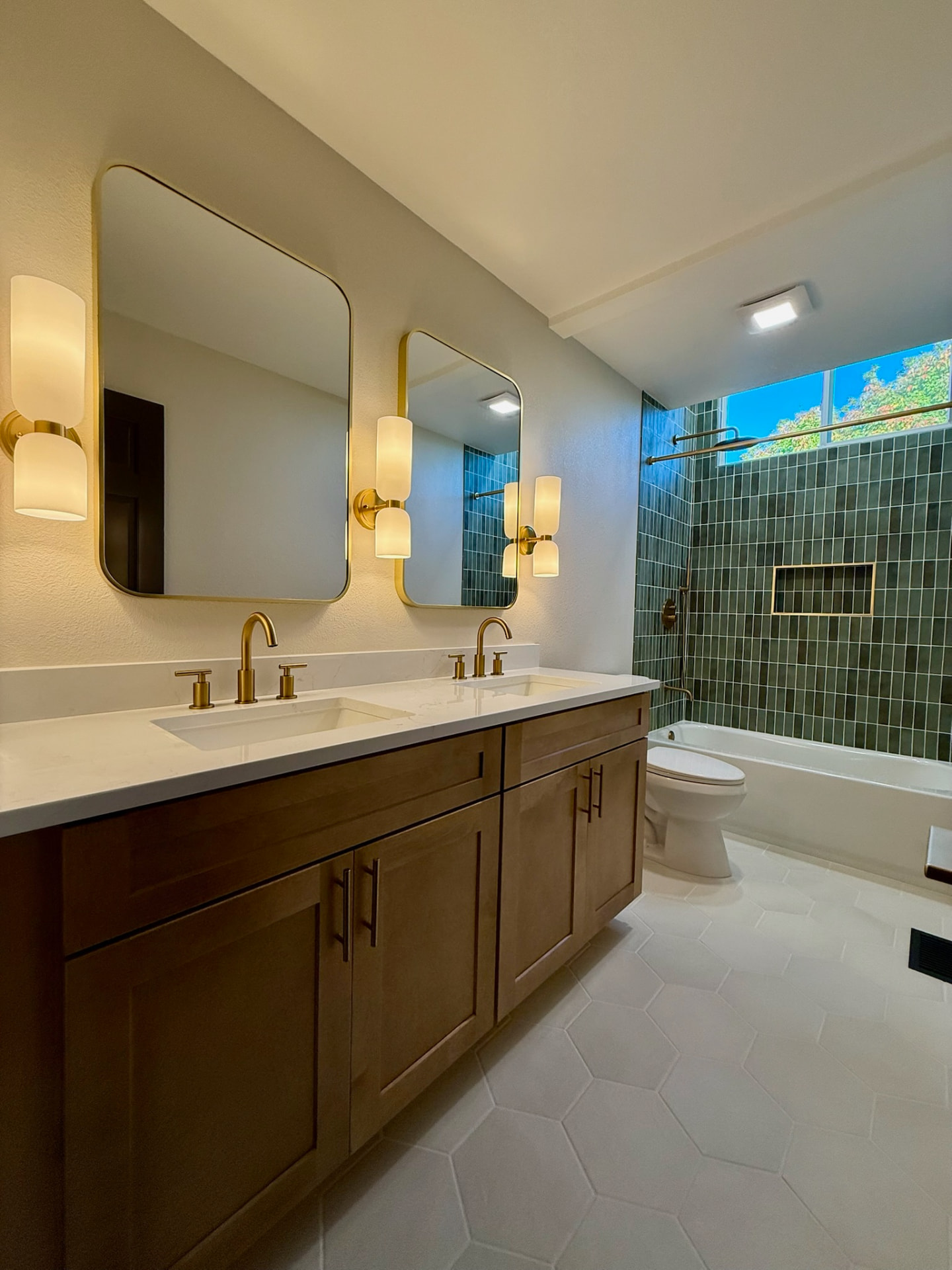 Double vanity with quartz counters, brass faucets, and framed mirrors